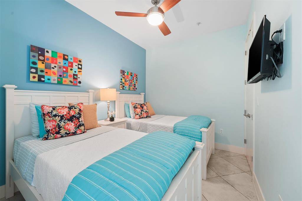 Bright and inviting second bedroom with tasteful furniture, TV and closet.