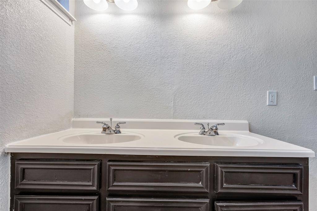 Primary bathroom vanity with dual sinks, featuring a white countertop and dark cabinets, under a set of overhead lights.  Lighted mirror will be installed!