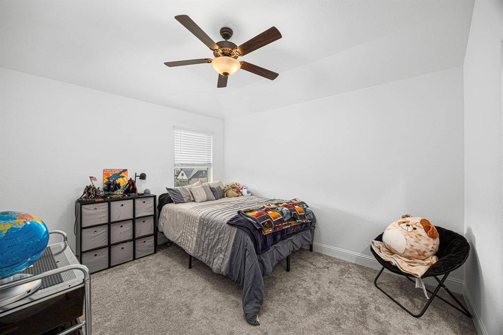 Secondary bedroom with ceiling fan, neutral walls and large window.