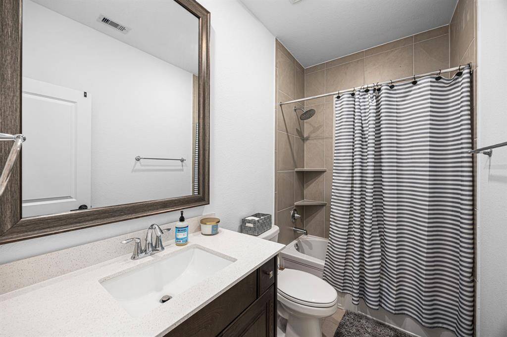 Secondary bathroom with custom mirror, tub/shower combo and chrome finishes.