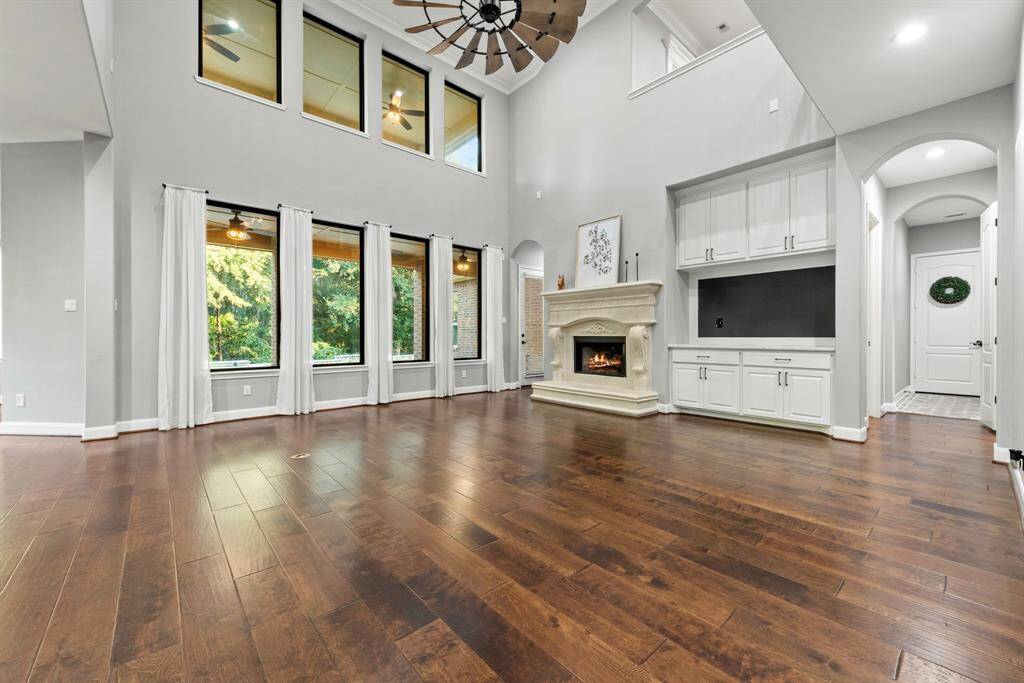 Two story windows in living room with built in storage, message board and cast stone fireplace.