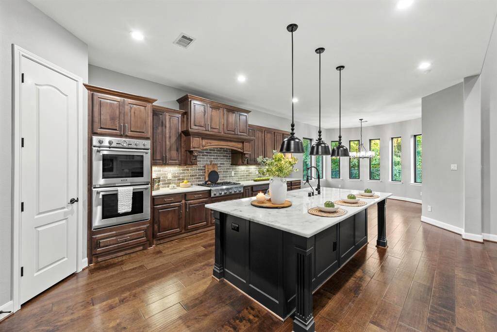 Bar seating for 3-4 with triple pendant lighting, electric in island and single vessel sink. Thermidor stainless steel appliances, double ovens and 6 burner gas range.