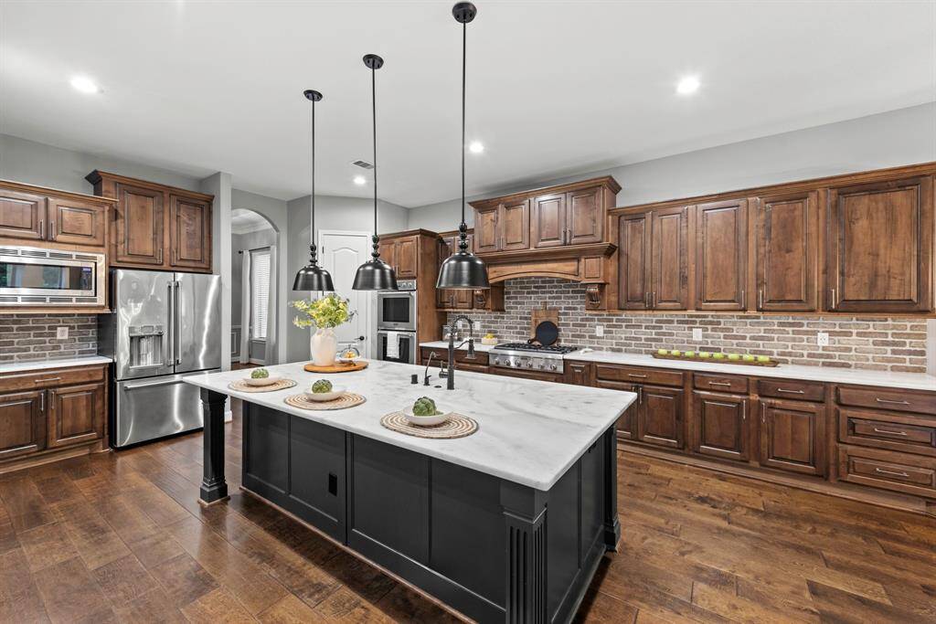 Warm stained cabinets and brick accents create a beautiful place for casual island dining. Corbels over range pull out for double sided spice racks.