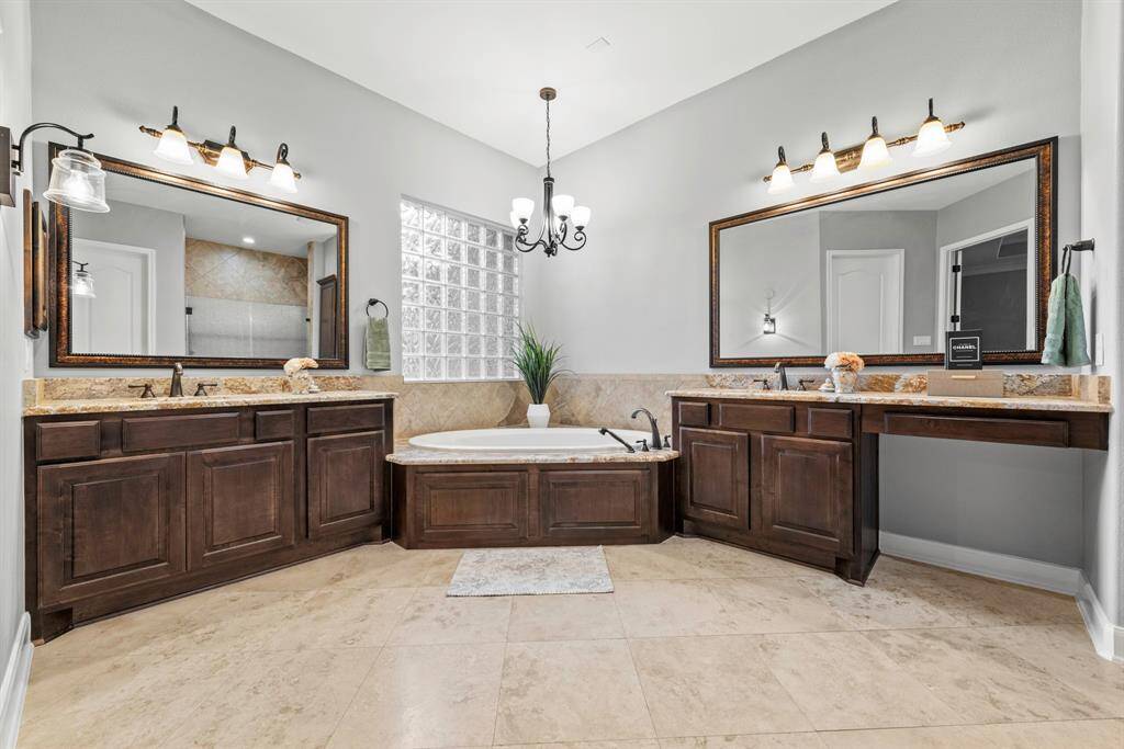Double vanity sinks with granite counters, jetted soaking tub, make station and travertine stone floors.