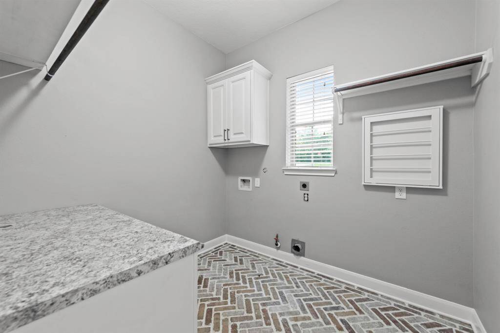 Front facing laundry room with upper and lower cabinets, drying racks and counters. Gas or electric hook ups for dryer
