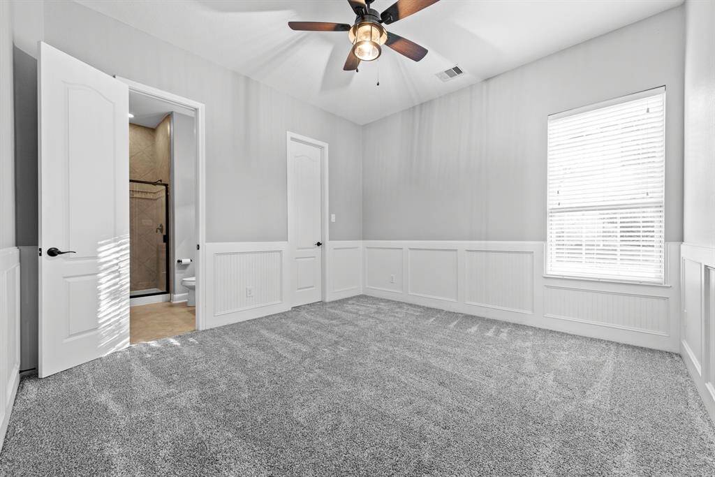 Downstairs secondary bedroom with private en-suite bathroom and headboard wall accents, walk in closet.