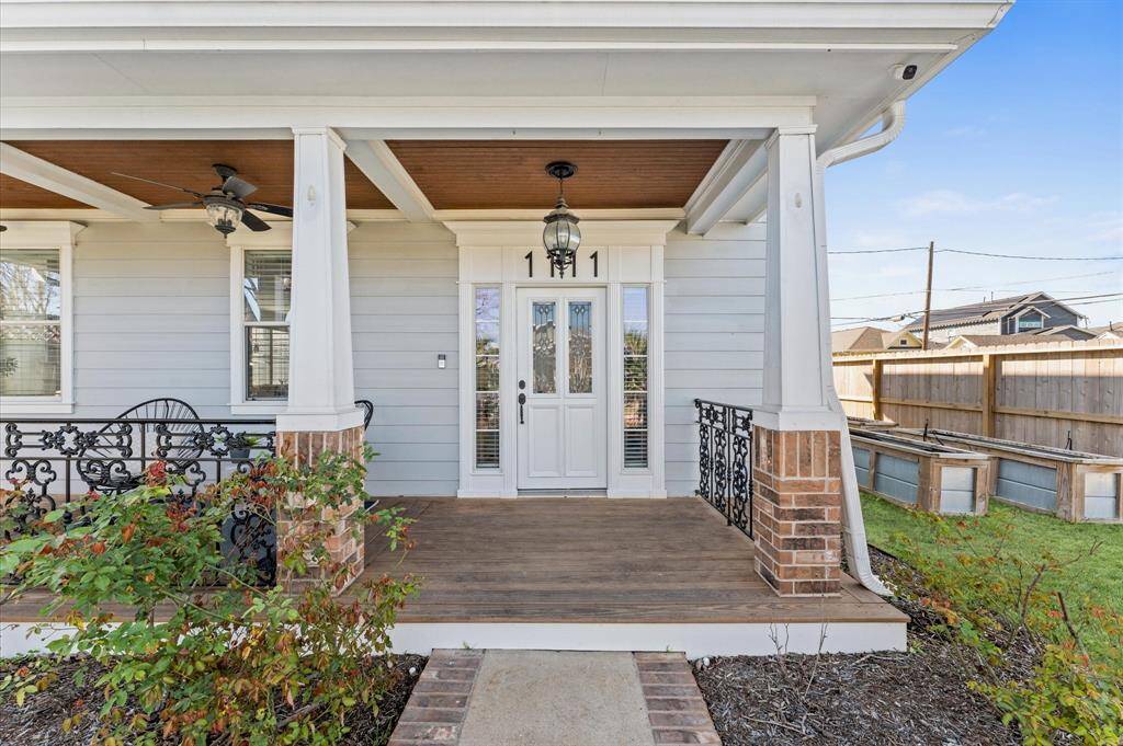 A front porch made for neighborly waves and quiet morning coffee. With Craftsman-style columns, a warm beadboard ceiling, and wrought iron railing, this inviting space is pure Southern charm.