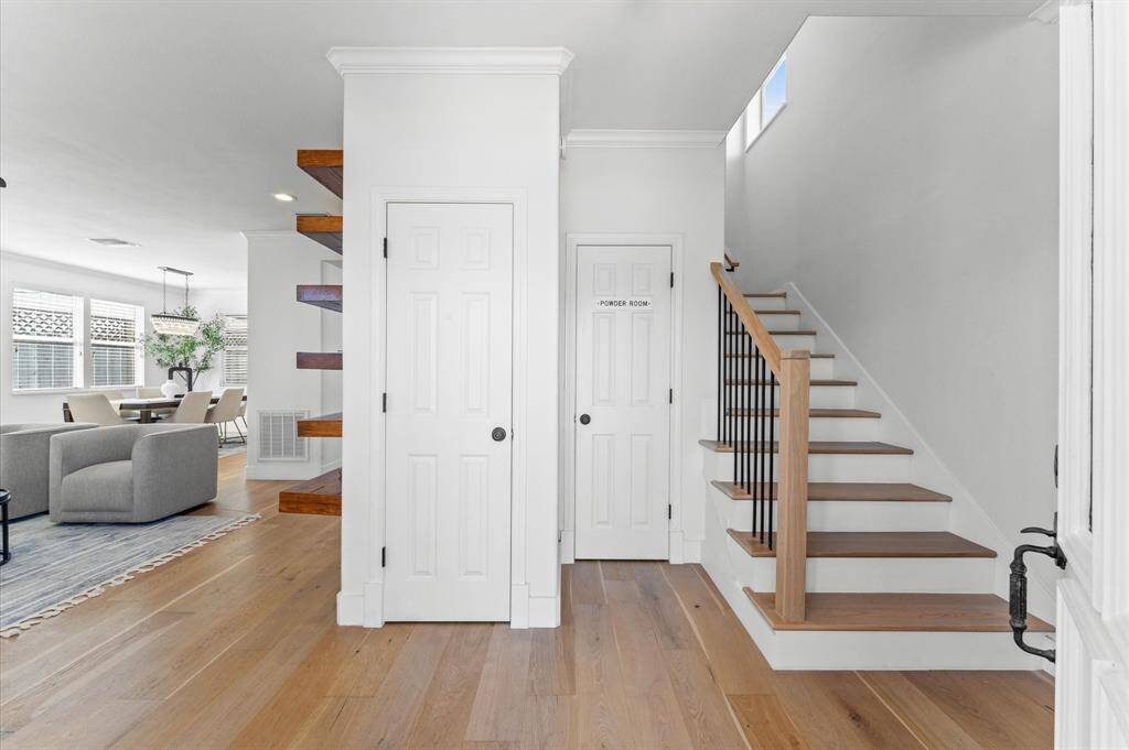 Smart, stylish, and functional—this foyer sets the tone with custom Elfa coat storage, floating shelves, and a sleek wood-and-metal staircase.
