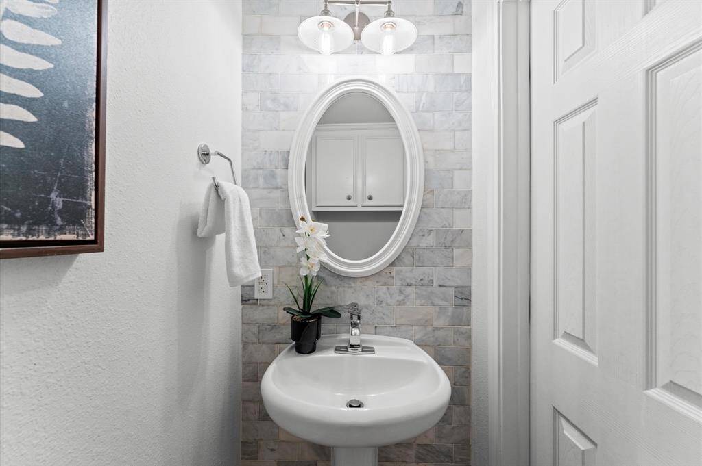 Even the powder room is a showstopper. Marble tile, elegant lighting, and a chic pedestal sink make this the kind of guest bath that gets compliments.
