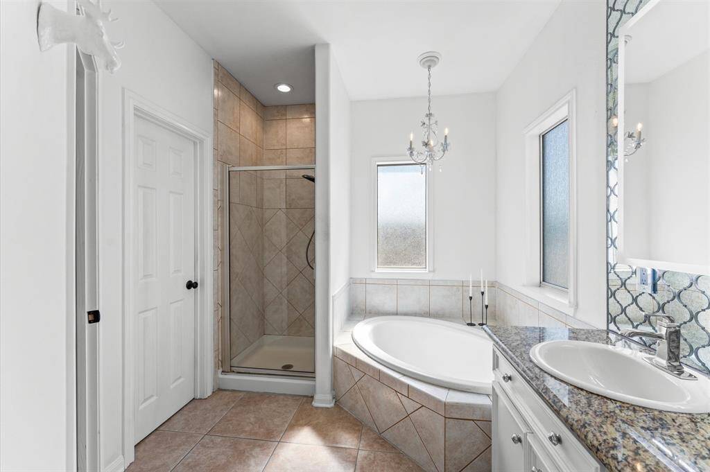 Soak the stress away in this spa-like retreat with a deep soaking tub, separate shower, and elegant chandelier.