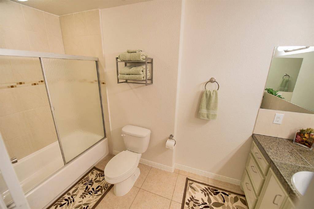 A spacious driveway with a gated entrance and privacy fencing, surrounded by lush greenery and mature trees, offering a serene and secure outdoor setting.