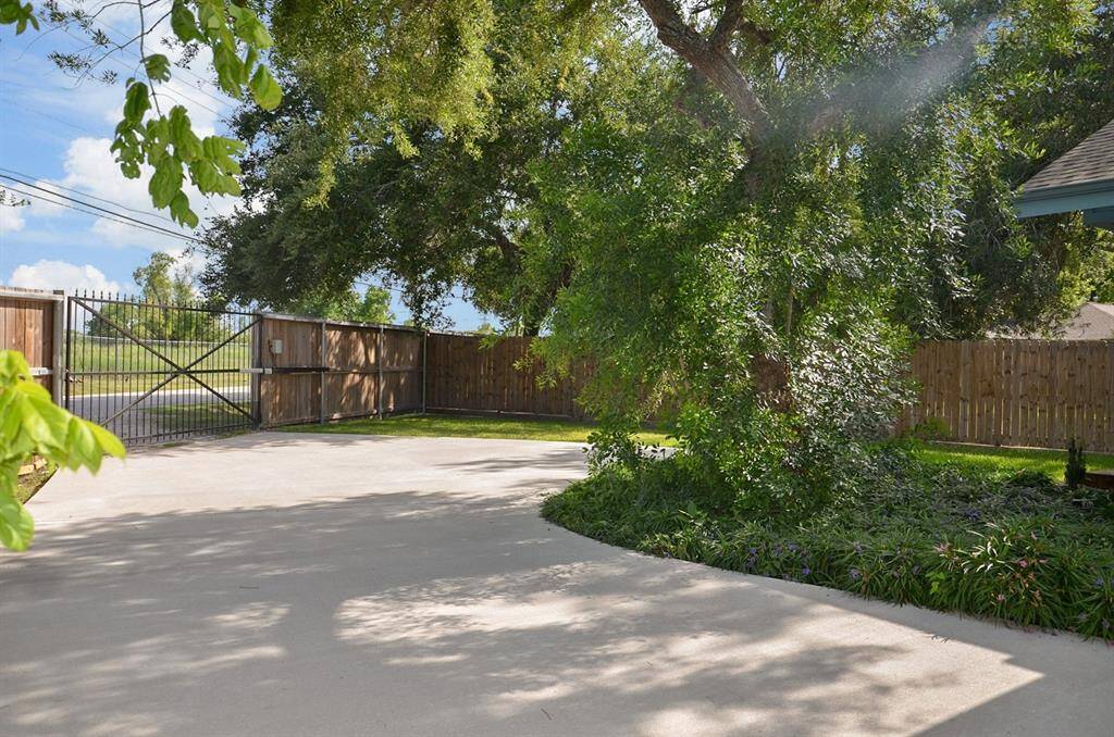 Large concrete driveway. There's a welcoming front porch, a picnic table for outdoor seating, and a fenced yard, surrounded by greenery for added privacy.