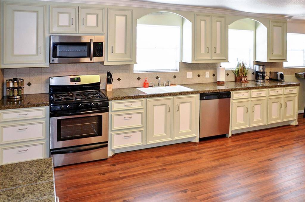 This spacious kitchen features modern appliances, ample cabinetry, and a large island with bar seating. The open layout and hardwood floors create a warm and inviting atmosphere, perfect for entertaining.