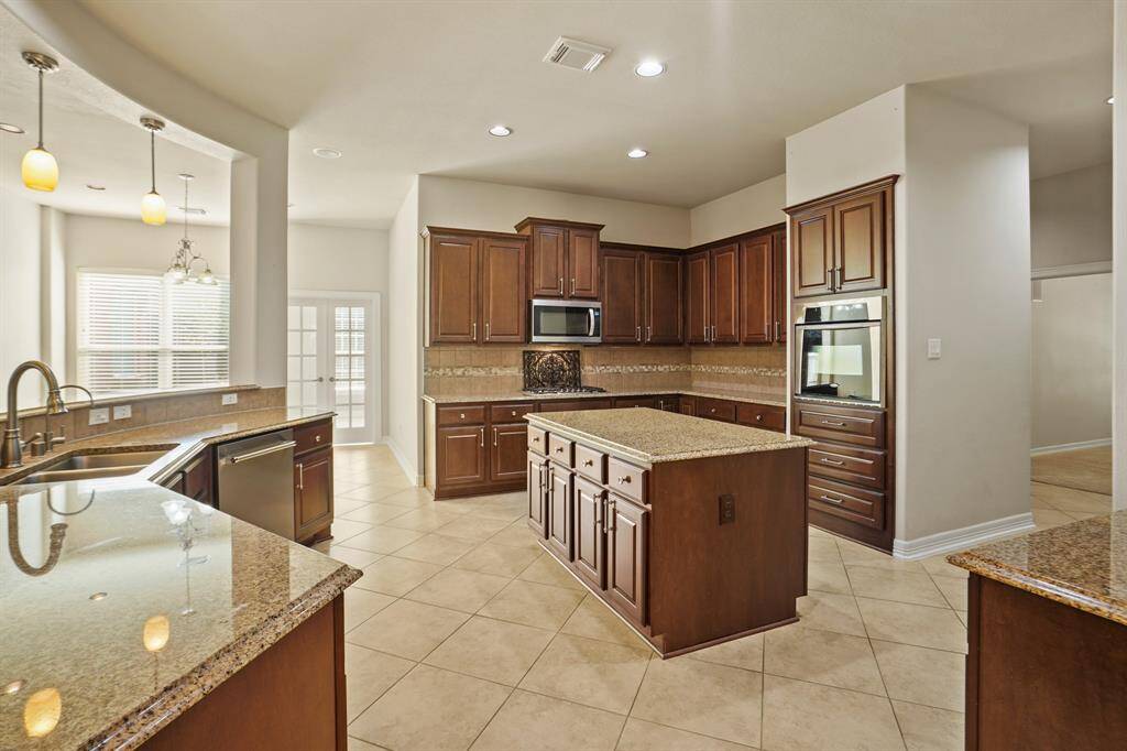 Granite counters, stainless steel appliances, and island with ample storage are highlights of the kitchen.