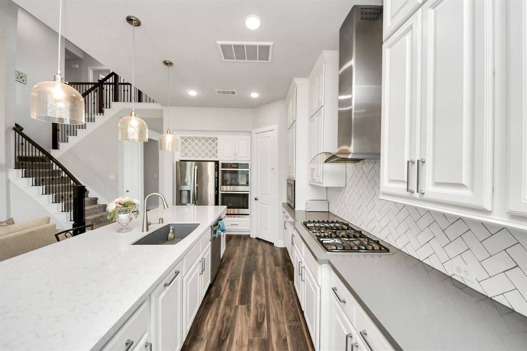 Quartz countertops that complements the beautiful cabinetry perfectly, while the eye-catching backsplash adds a contemporary flair to the overall design