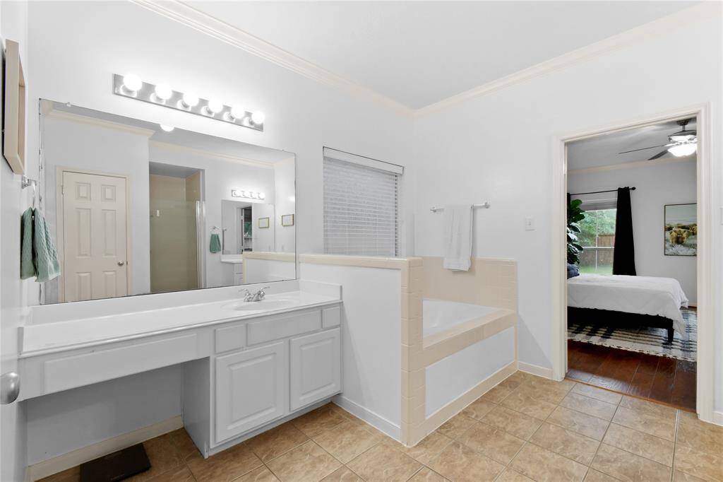 The en'suite bath is easy to share with dual vanities including a make-up seating area, jetted tub, and glass shower.