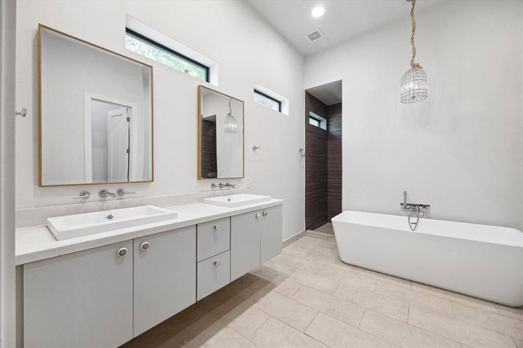 The primary bathroom features tile floors, dual sinks, huge dual sided walk-in shower, and soaking tub with chandelier above!