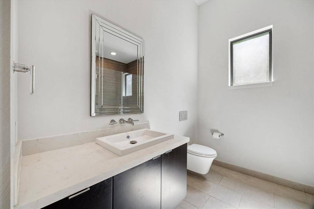 Secondary bathroom features tile floors and a long vanitywith plenty of counter space. There are also floating shelves behind the door between the bedrooms.