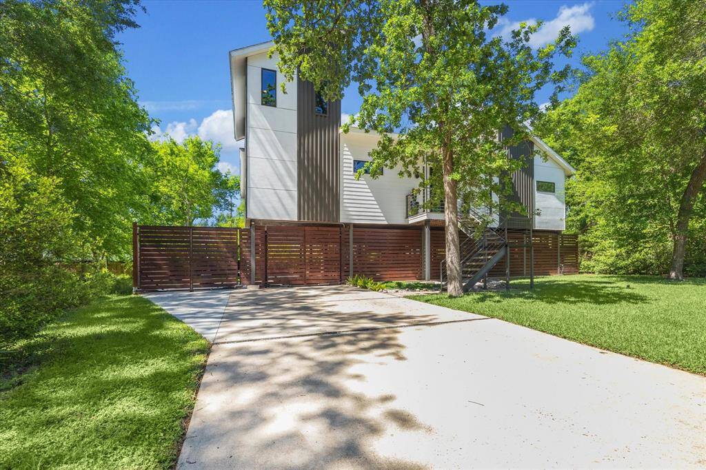 Large driveway leading up to electric gates that open up to a large patio area and carport