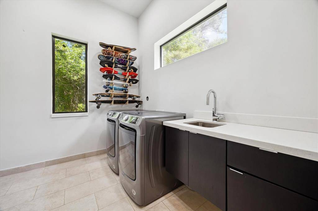 The laundry room features tile floors,washer and dryer connections, large windows, stainless steel sink, counter space, andplenty of storage space.