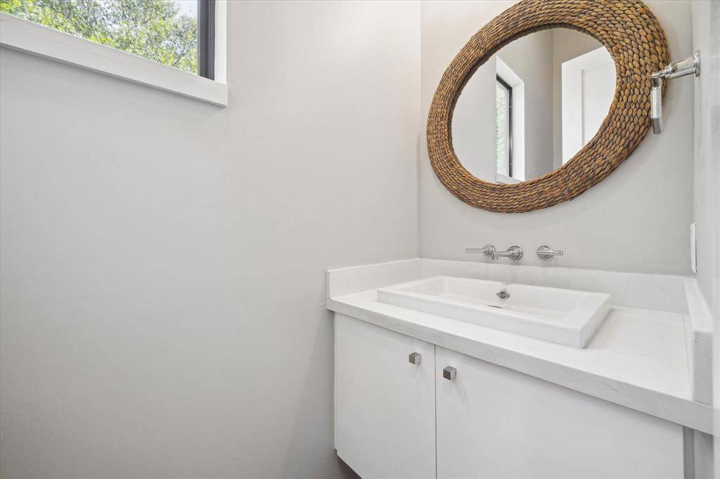 The half bathroom is right off the living room and has a modern sink and large window.