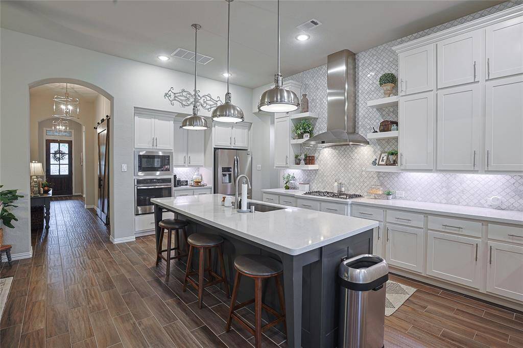 Custom backsplash, under cabinet lighting and stainless appliances highlight the kitchen space