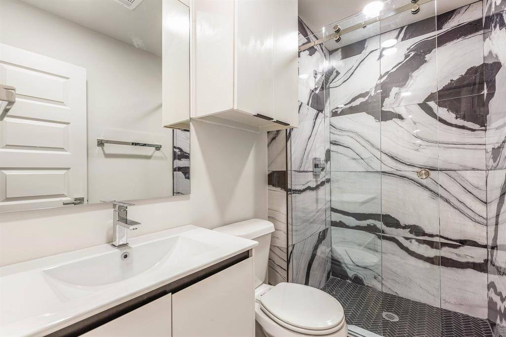 The primary ensuite bathroom features an eye-catching marble tile accent wall.