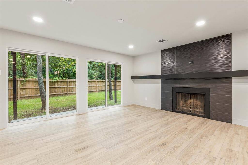 The living room boasts a beautiful scenic view of the outdoors and an expansive mantel above the wood burning fireplace.