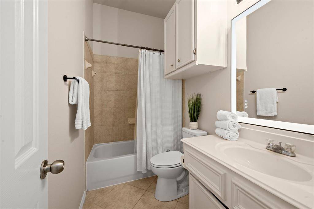 Shared full bath with single vanity, tile flooring and a tub/shower combo.