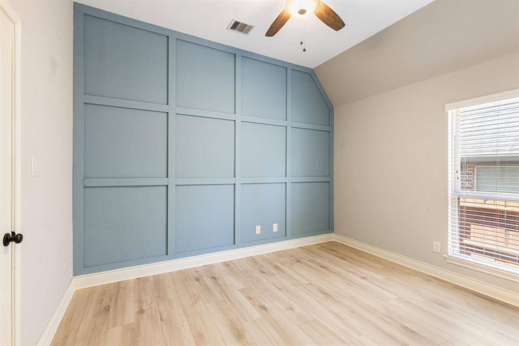 Secondary bedroom, another of the homes welcoming bedrooms has light white oak floors and panel accent wall.