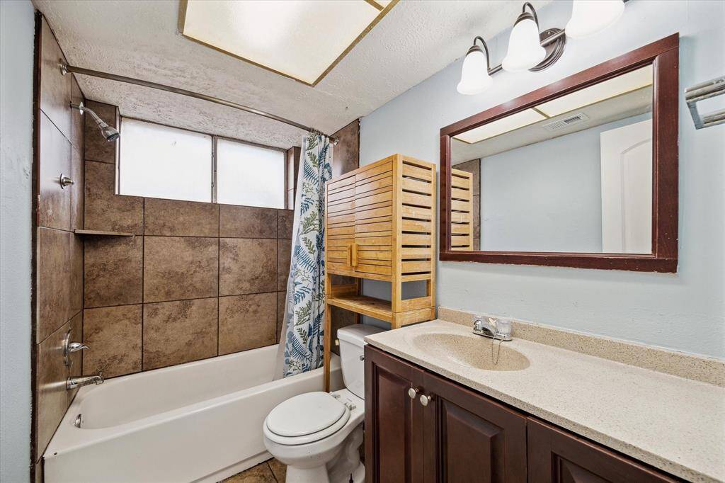 The guest bathroom features a tiled shower-tub combo with a large window for natural light.