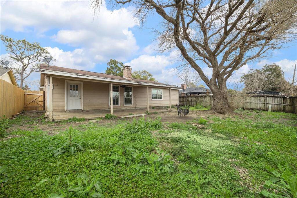 The large backyard has a covered back porch and a mature tree.