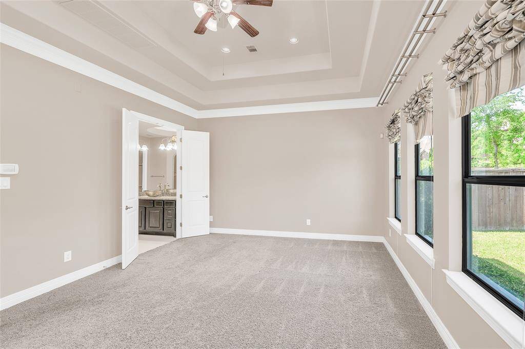 Spacious primary bedroom suite with tray ceiling and double doors to the ensuite.