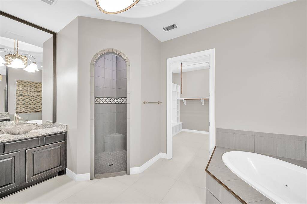 Arched entry with tile accents leading into the custom oversized walk-in shower.