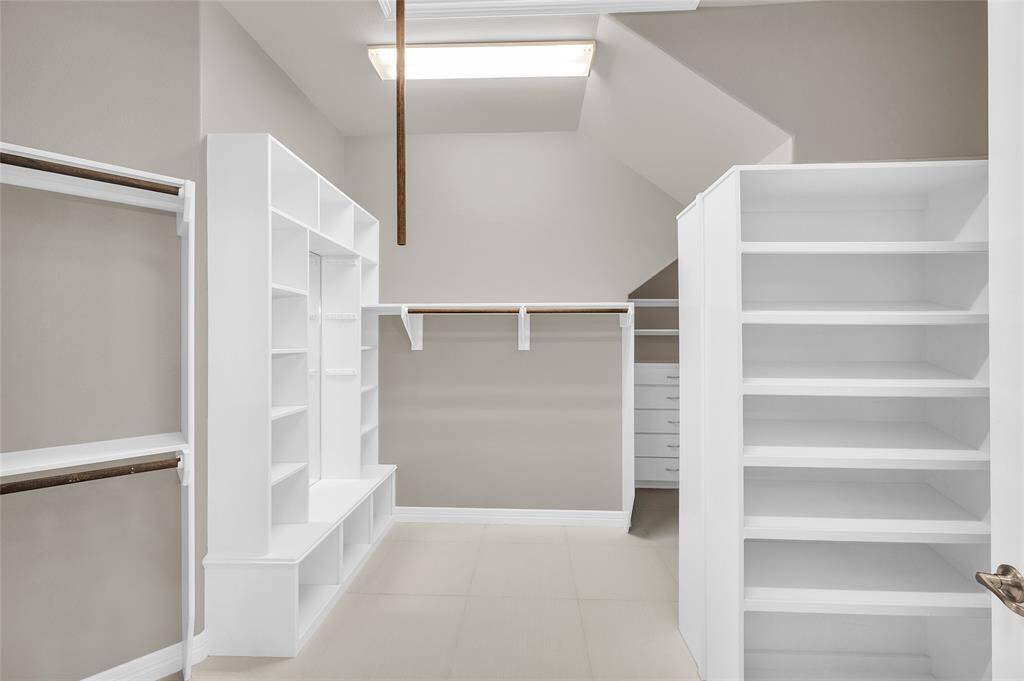 Expansive custom closet with a 6-ft shoe island and built-ins throughout.