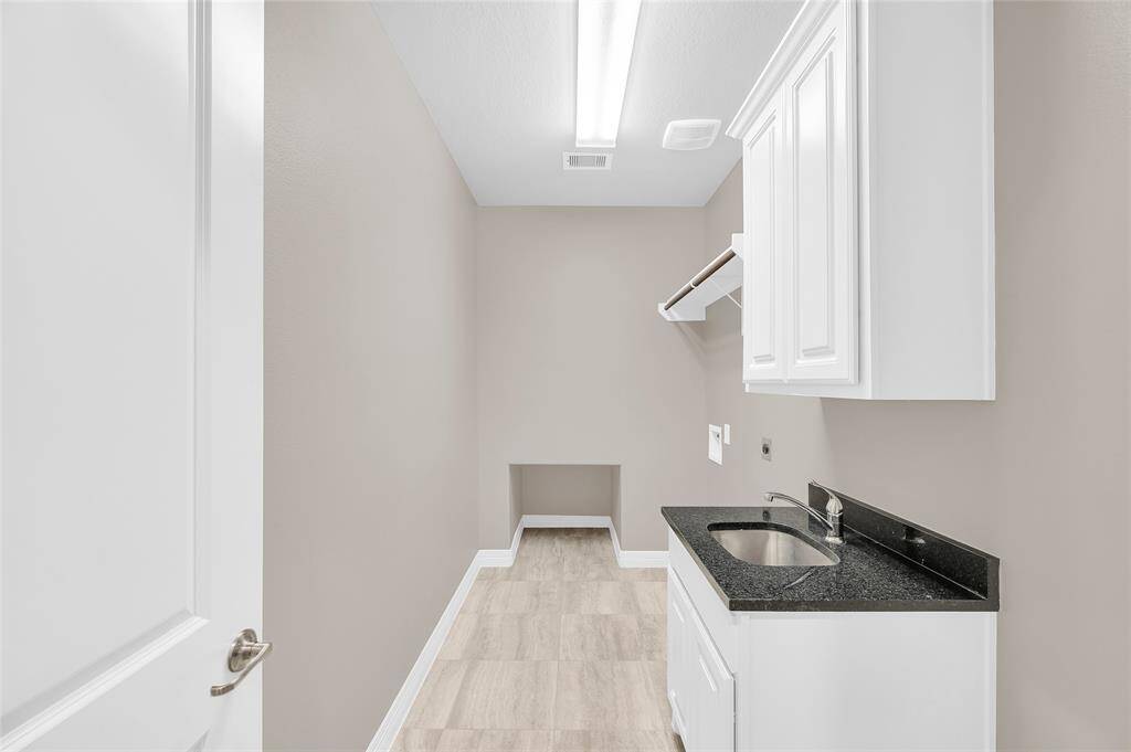 Spacious laundry room featuring a utility sink and custom cabinetry.