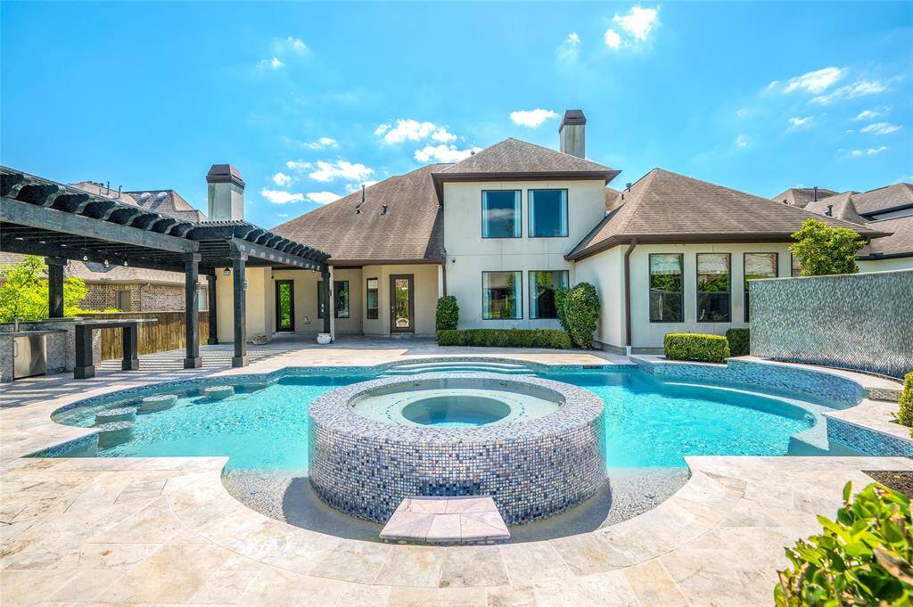 Elevated hot tub with a cascading waterfall seamlessly flowing into the pool.