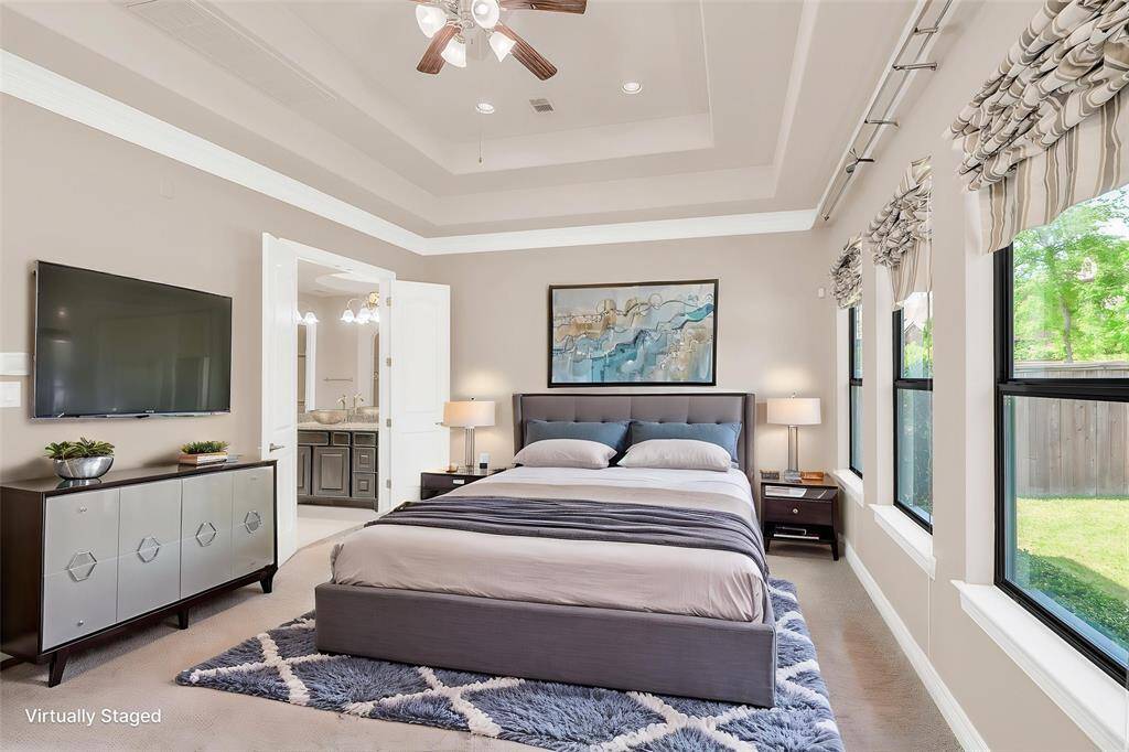 Primary bedroom suite with large windows, a tray ceiling, and a luxurious ensuite bathroom.