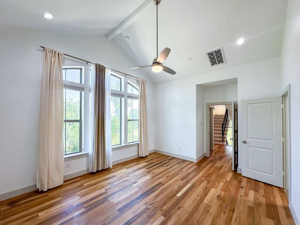 Another view of this large primary bedroom on the third floor, with soaring ceilings, oversized windows, and gorgeous hardwood floors. Vacant and ready for immediate move-in.
