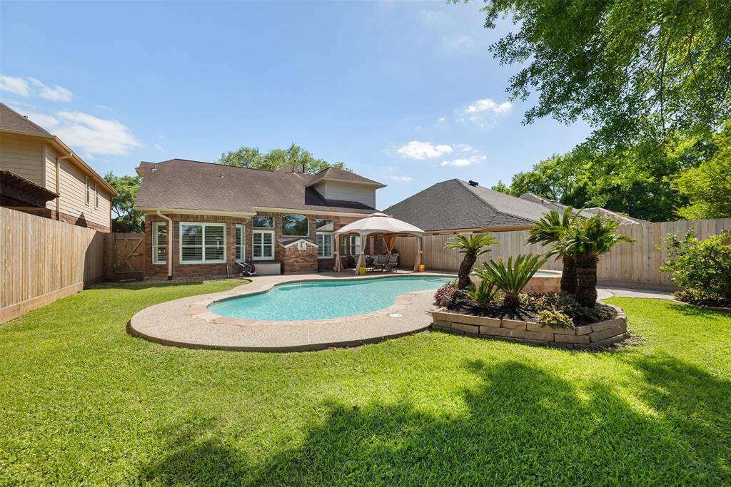 This charming backyard features a pristine pool surrounded by lush greenery and a cozy seating area under an umbrella—creating the perfect space for both relaxation and entertaining. Imagine yourself unwinding here, enjoying the peaceful atmosphere and warm outdoor gatherings. Don’t miss out on this inviting oasis—schedule your tour today!