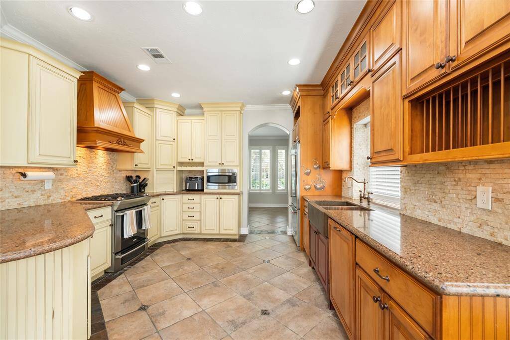 A Chef's Retreat! This thoughtfully designed kitchen exudes traditional warmth with its rich wood cabinetry, gleaming granite countertops, and high-end stainless steel appliances. Recessed lighting creates an inviting atmosphere, while the built-in oven and wine rack add both function and style. A large window above the sink fills the space with natural light, making it the perfect setting for both everyday meals and special occasions.
