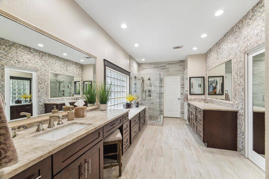 The primary bath as recently been updated and features a stone herringbone tiled wall, seamless shower enclosure, dual vanities and vanities with plenty of storage. The owners left the plumbing for soaking tub in place for you.