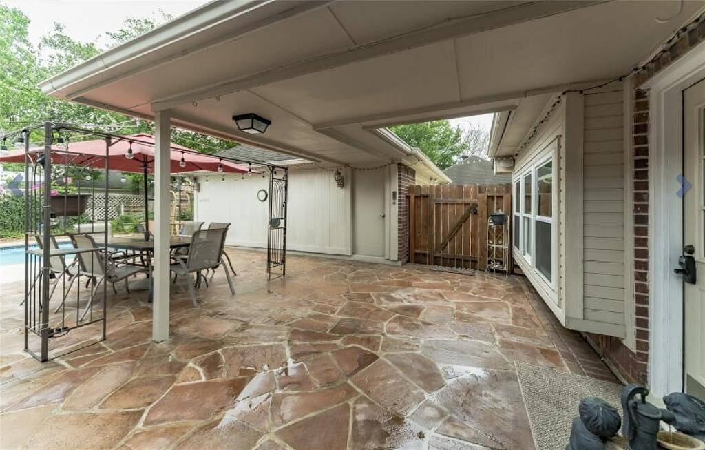 Covered patio to this serine back yard with a pool