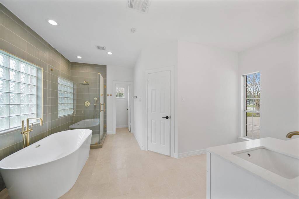 Primary Bathroom offers a relaxing soaking tub and glass-enclosed walk-in shower.