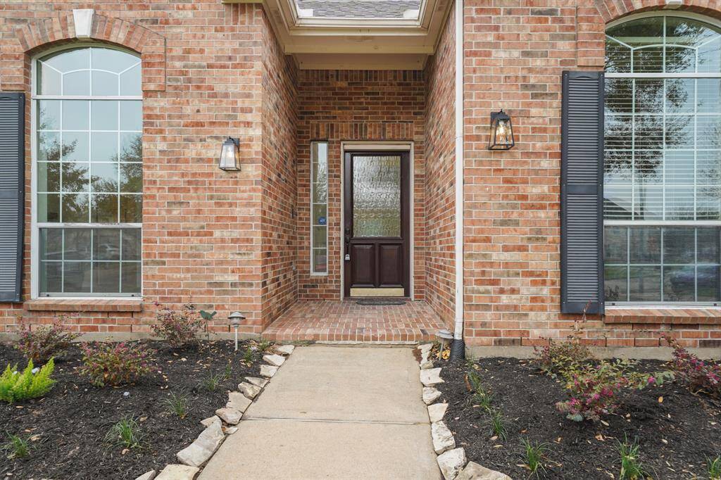 The grand entrance showcases beautiful arched windows and a stately front door, creating a warm and inviting first impression for guests and homeowners alike.
