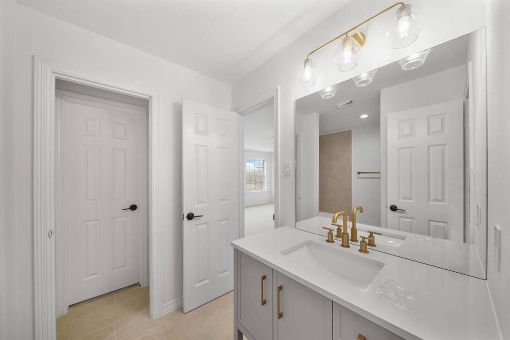 The bathroom features a sleek sink with ample cabinet storage.