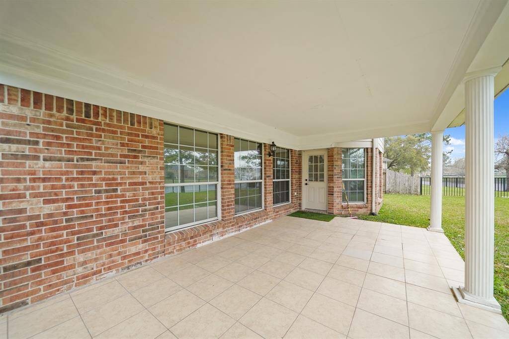 This spacious covered patio offers a shaded retreat for relaxing, grilling, or entertaining guests while enjoying the open backyard view.