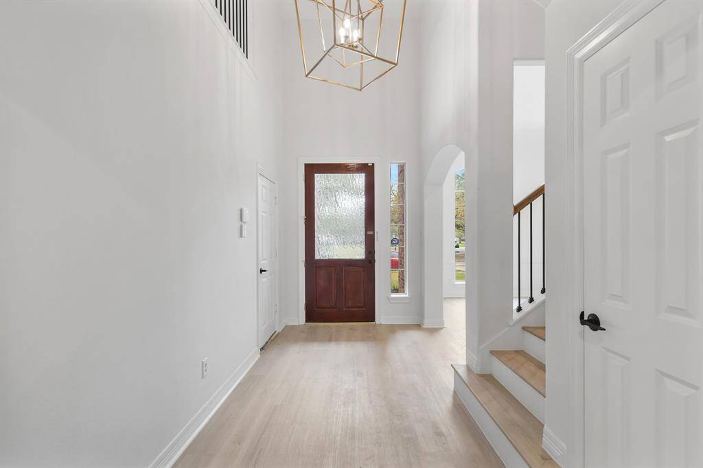 From inside the home, the foyer offers a stunning view of the elegant front door with soaring ceilings and abundant natural light.