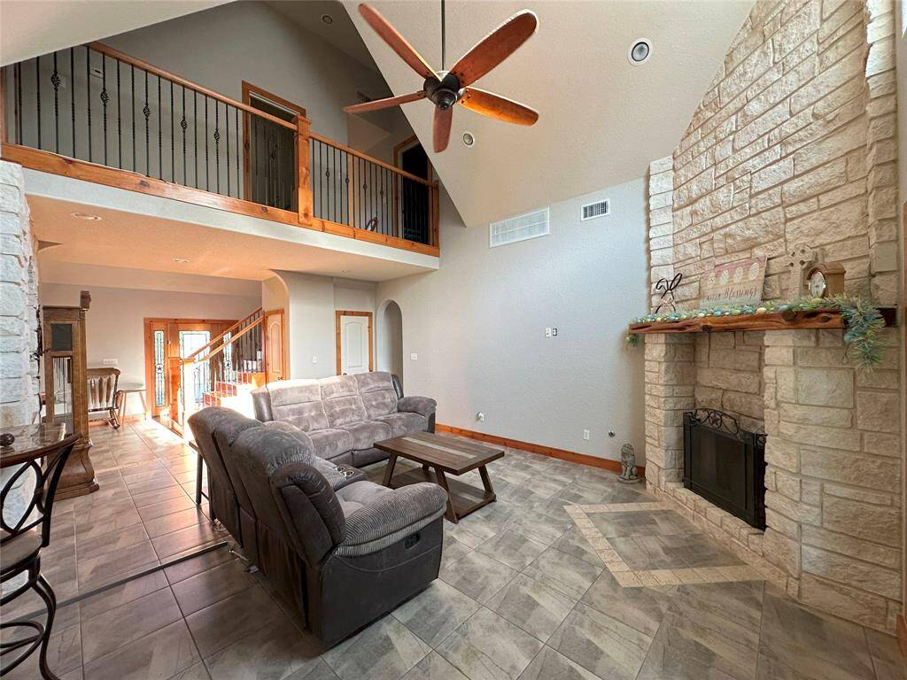 The giant living room features a beautiful floor to ceiling stone fire place and a balcony from the first floor looking into the room and out of the beautiful giant windows.
