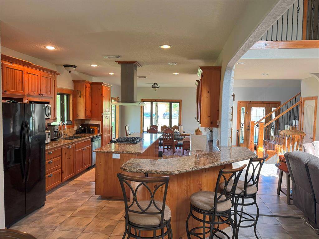 This gigantic kitchen features a large island, bar countertop, and open concept plan. The stainless steel appliances and granite countertops are the finishing to this beautiful space.